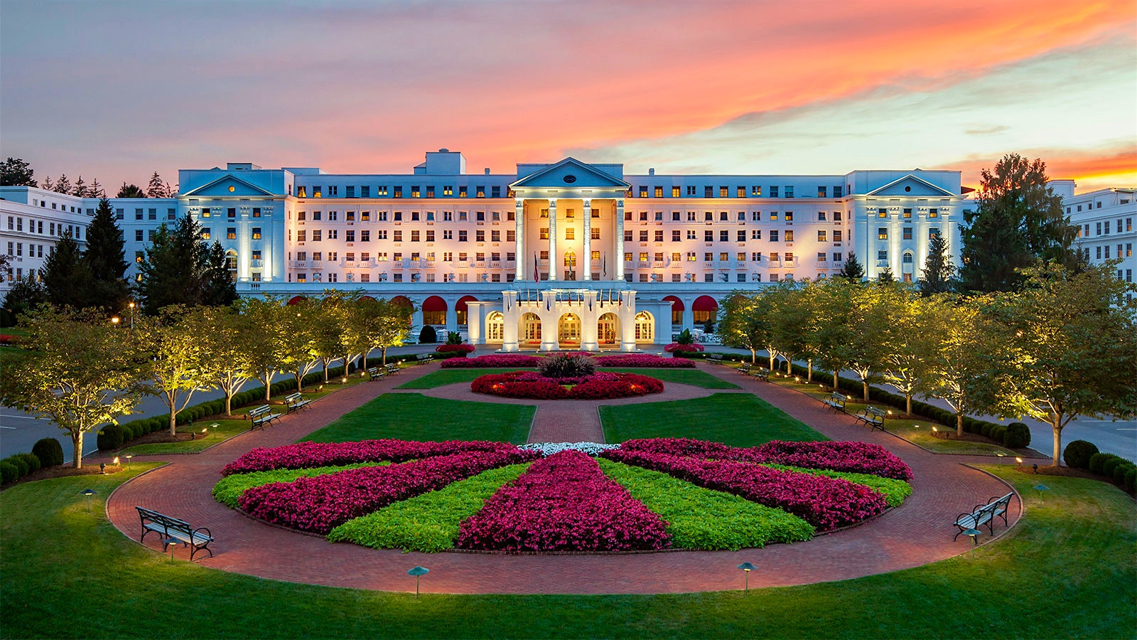the Greenbrier Resort’s white neoclassical exterior, with columns, and gardens with maroon flowers